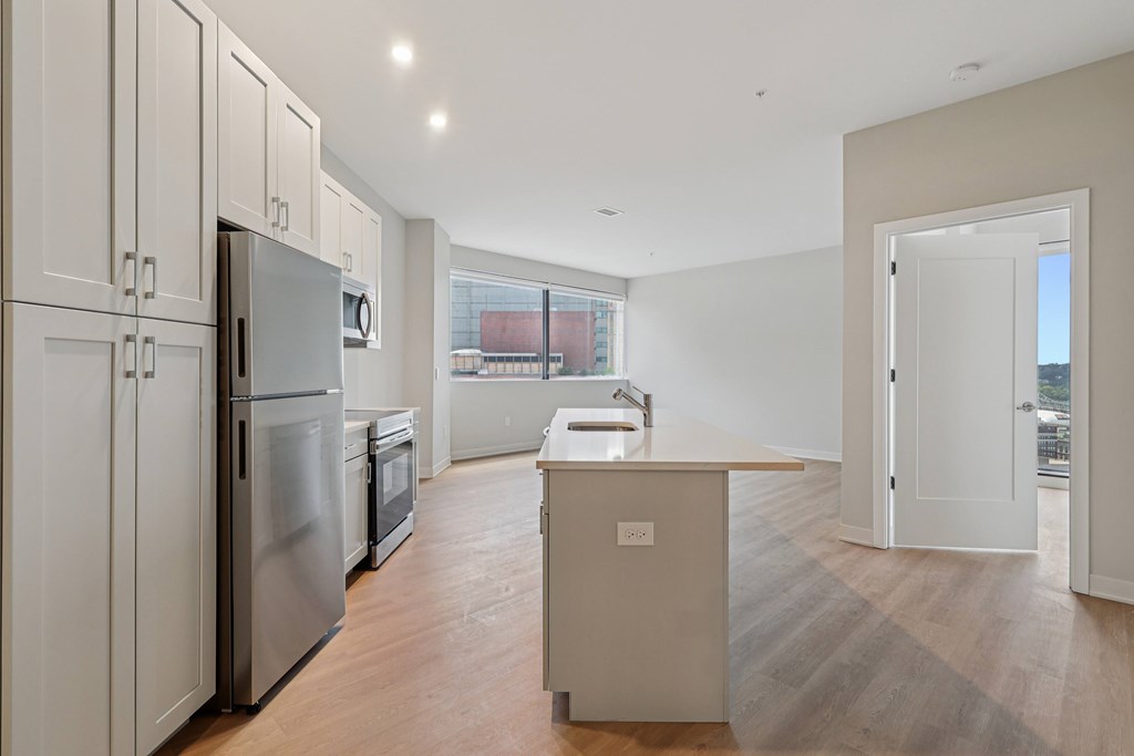 A kitchen with a refrigerator, sink, and cabinets.