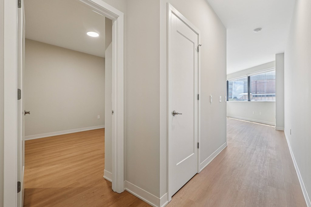 A long hallway with white doors and wood floors.