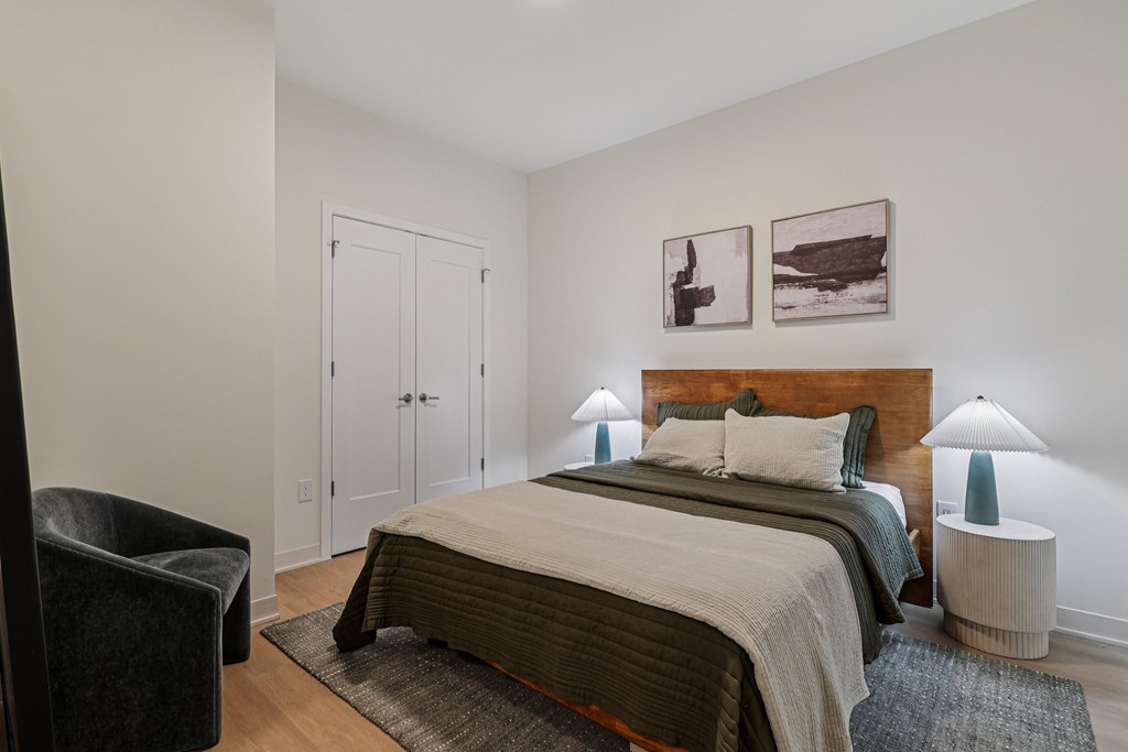 A bedroom with a large bed and two lamps.