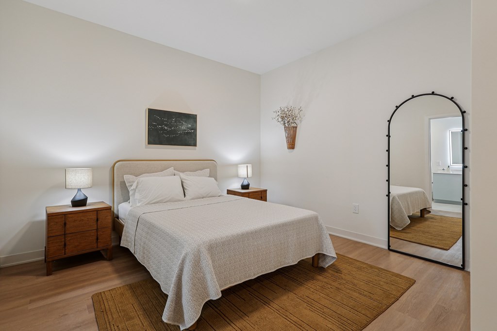 A bedroom with a bed, nightstands, and a mirror.