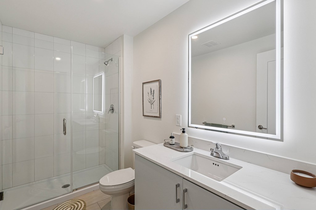 A white bathroom with a toilet, sink, and mirror.