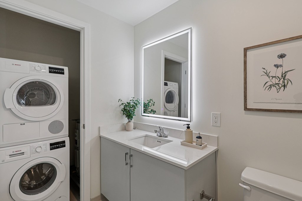 A small bathroom with a washing machine in the doorway.