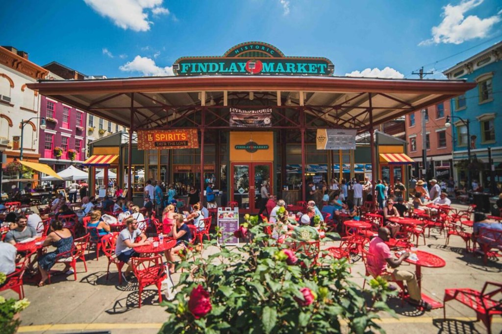 A busy outdoor market with people sitting at tables.