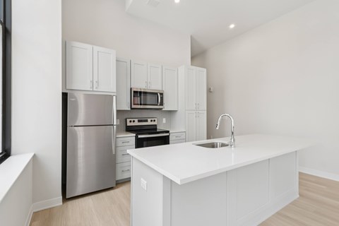 A modern kitchen with white cabinets and stainless steel appliances. A modern kitchen with white cabinets and stainless steel appliances at LiveWell Apartments, Pittsburgh 15222