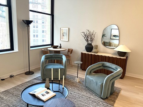 A living room with a blue chair and a round table with a book on it.