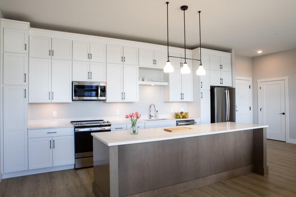 A modern kitchen with white cabinets and a central island. at The Pearl, Fort Wayne, IN
