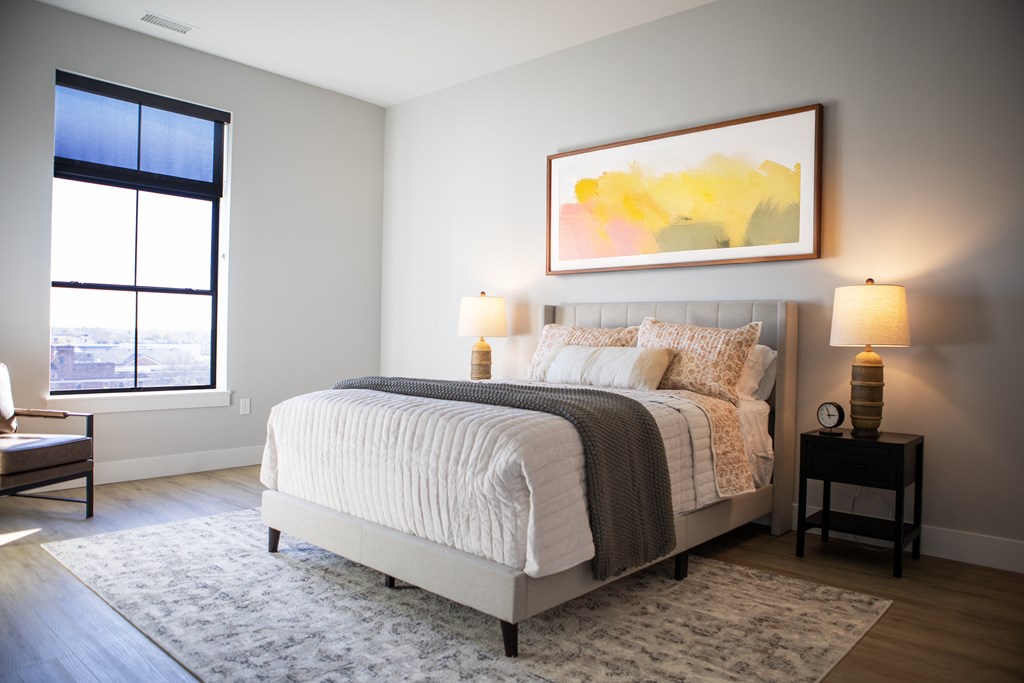 A bedroom with a large bed and a painting on the wall. at The Pearl, Fort Wayne, IN