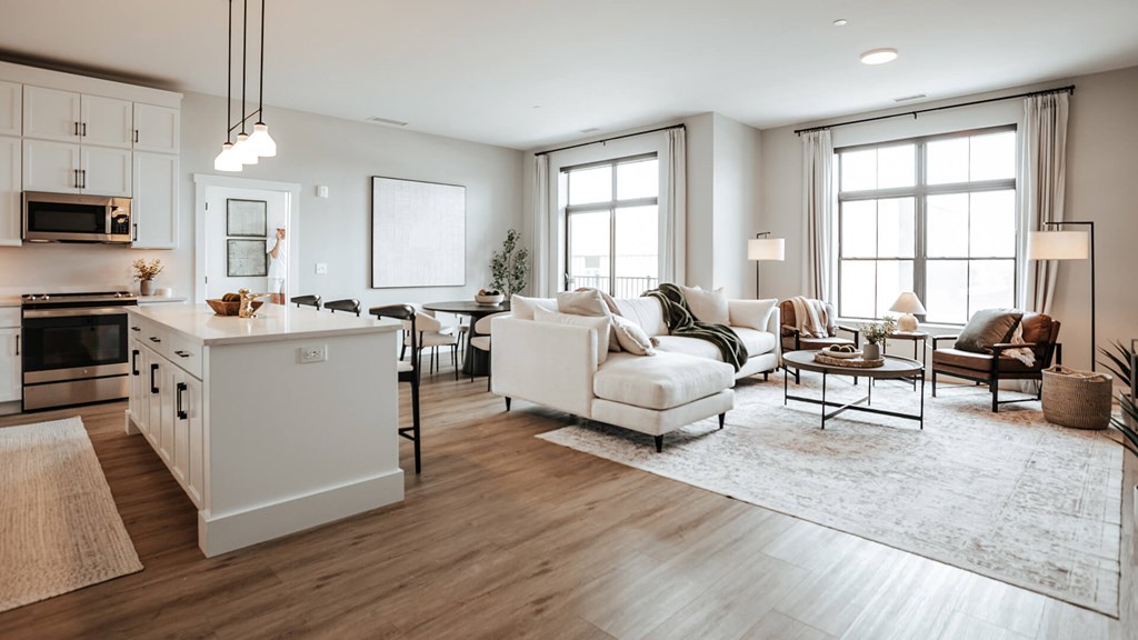 A modern kitchen with white appliances and a dining area with a white sofa and chairs. at The Pearl, Fort Wayne, IN