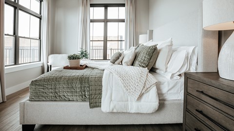 A bedroom with a bed covered in a green and white comforter.