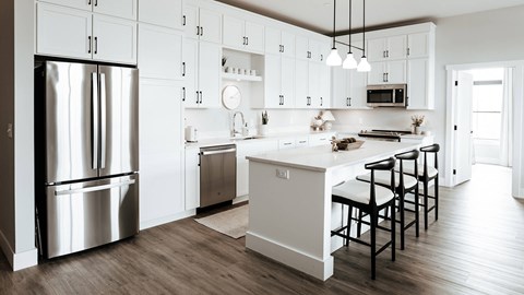 A modern kitchen with a white color scheme and stainless steel appliances.