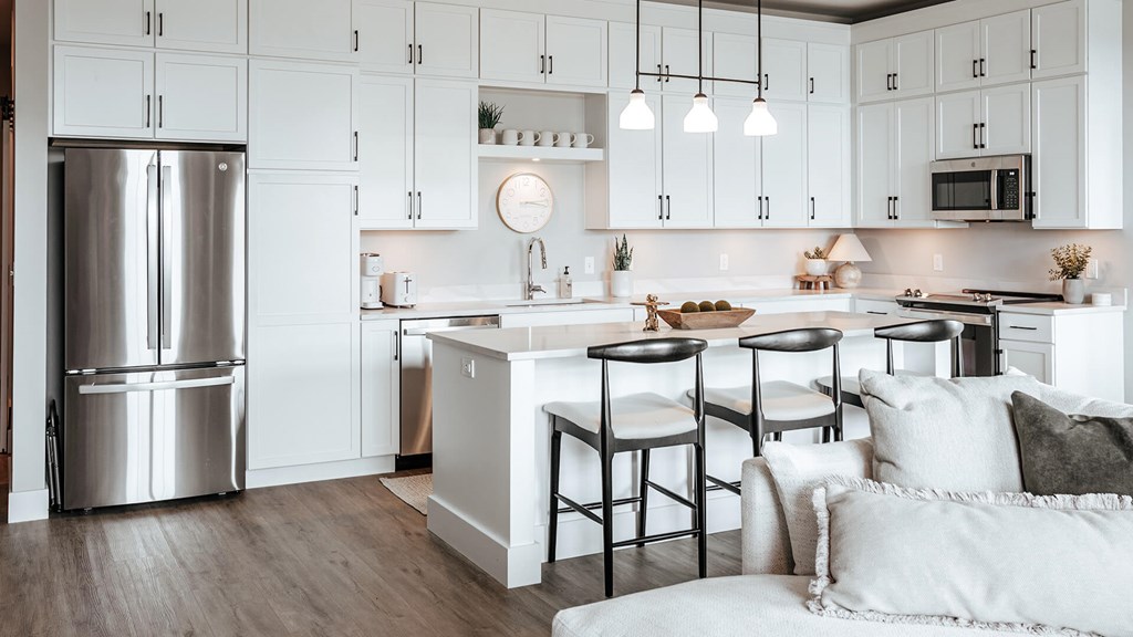 A modern kitchen with a large island and stools. at The Pearl, Fort Wayne, IN