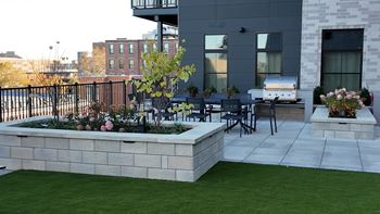 A patio with a table and chairs and a planter box with flowers. at The Pearl, Fort Wayne