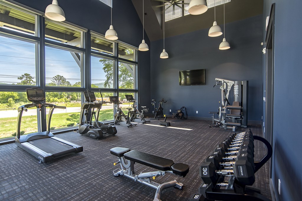 a gym with cardio machines and windows with a view of a golf course