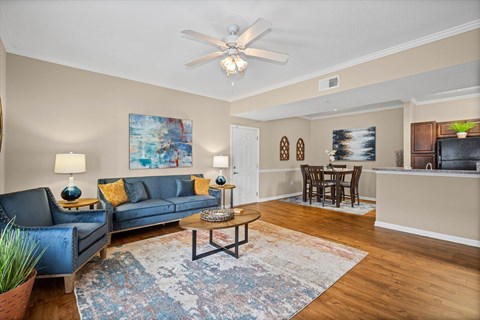 A living room with a blue couch and a painting on the wall.