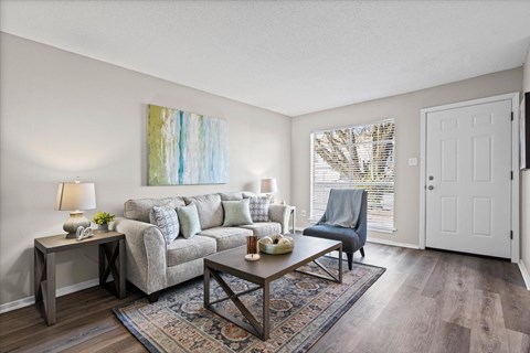 A living room with a grey couch, a wooden coffee table, and a painting on the wall.