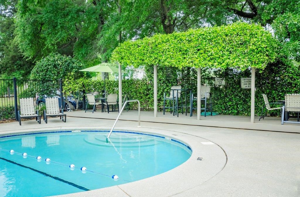a swimming pool with a fountain  and a patio with chairs