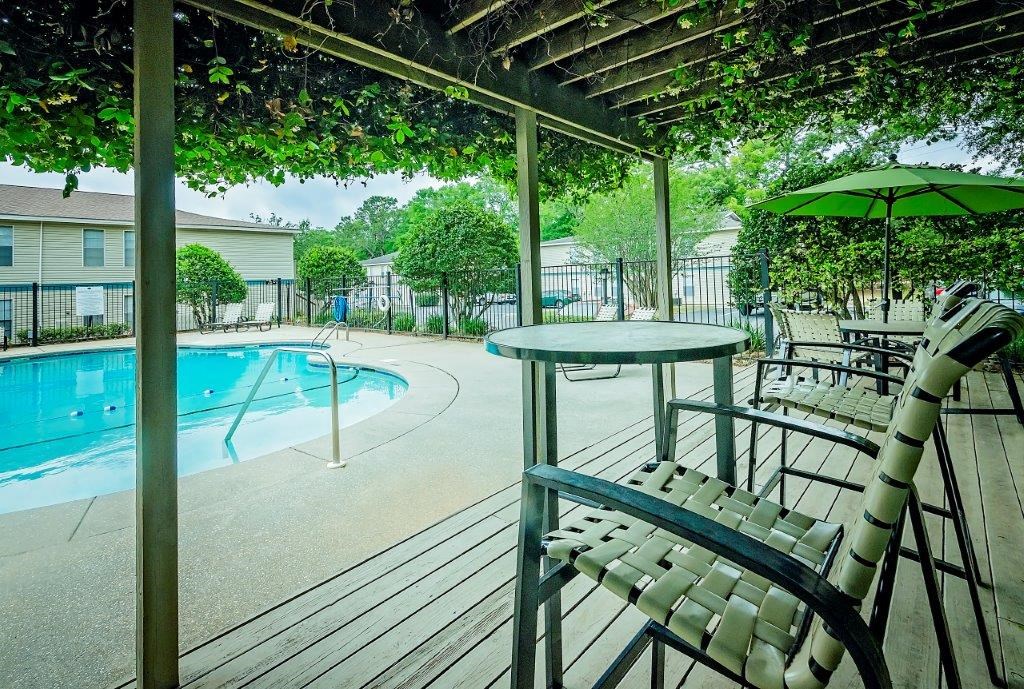 a patio with chairs and a table next to a swimming pool