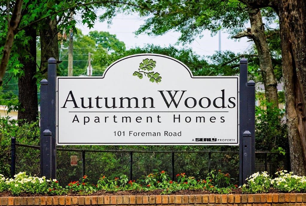 a sign for autism woods apartment homes in front of trees