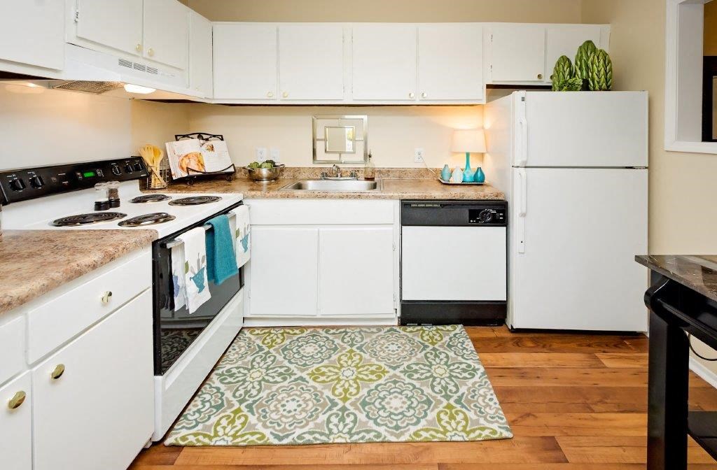 a kitchen with white appliances and a rug on the floor