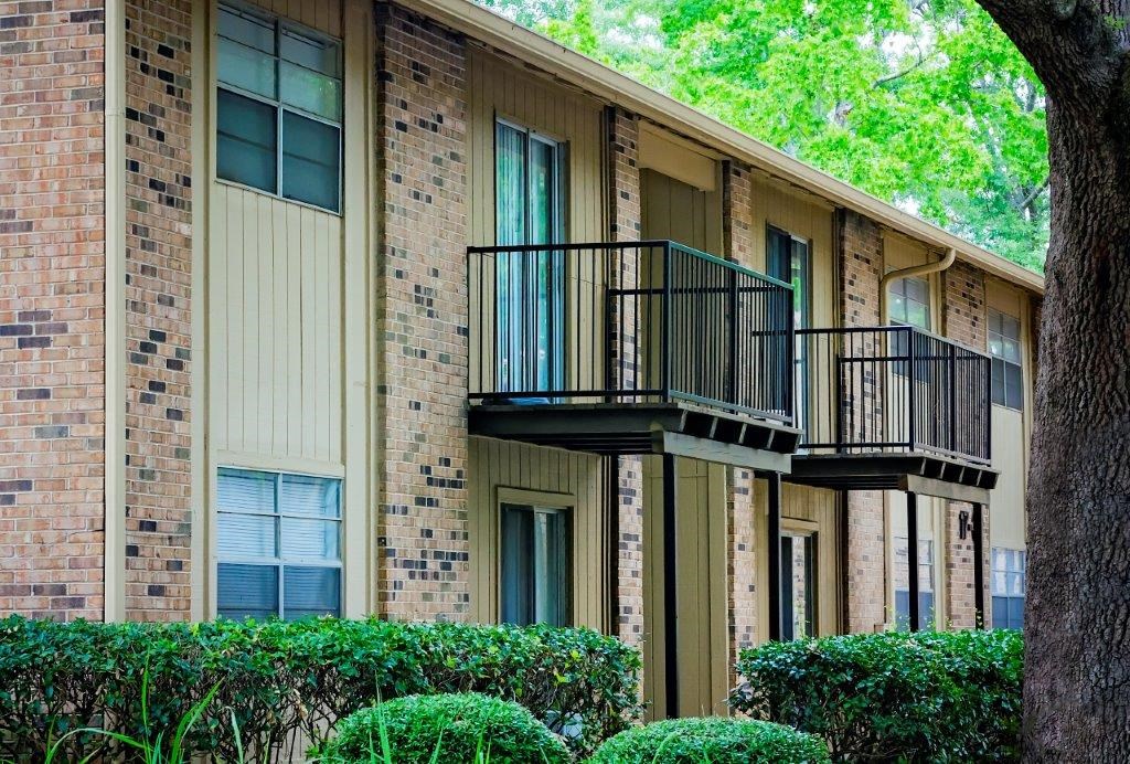 an apartment building with two balconies and bushes