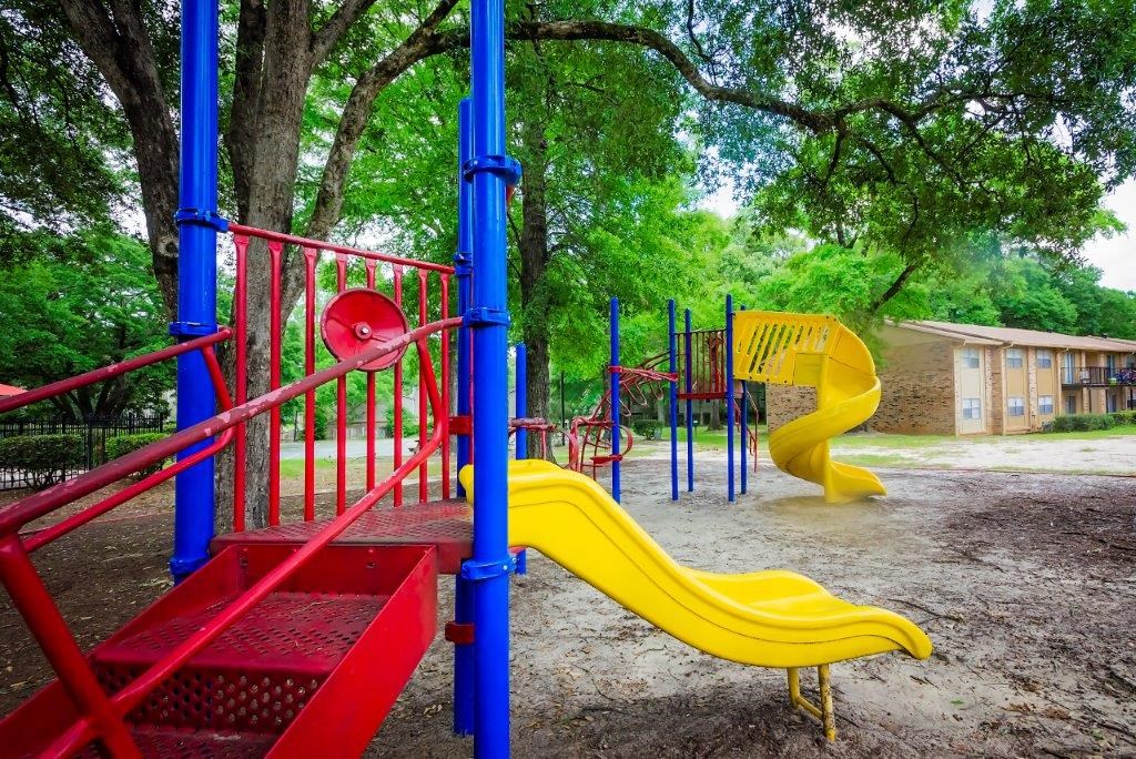 a playground with a yellow slide and a red frame