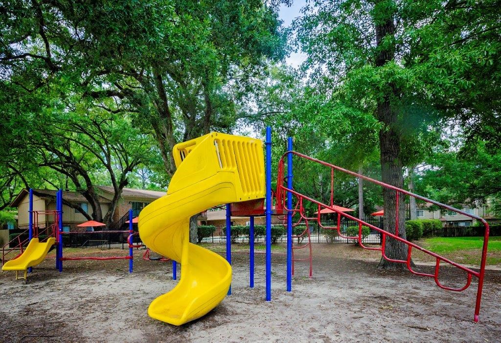 a playground with a yellow slide and a red slide