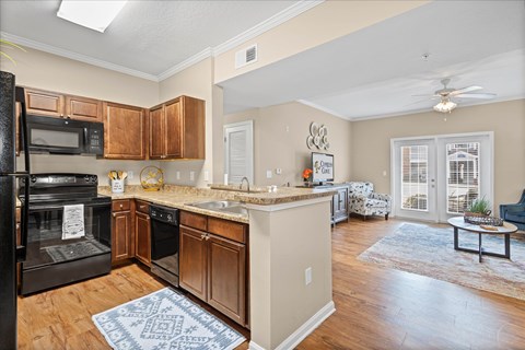 A kitchen with a black stove top oven and wooden cabinets.