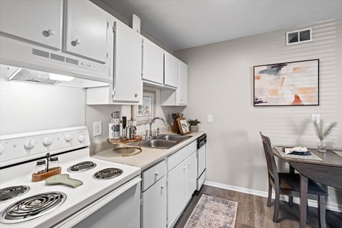 A modern kitchen with white cabinets and a stove top oven.