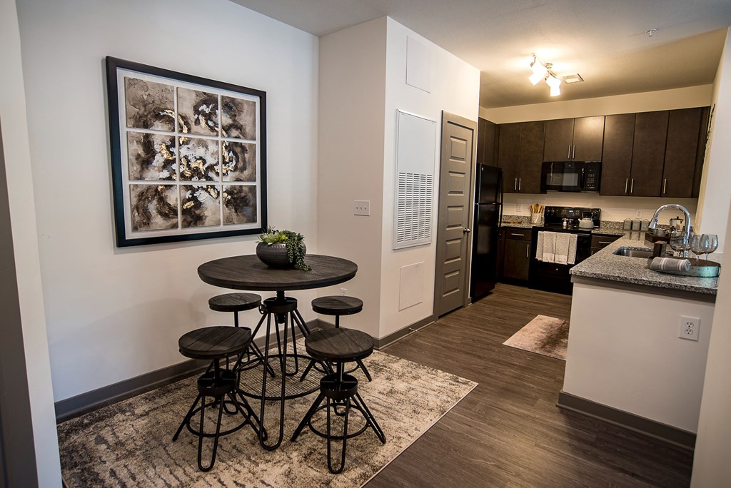 a living room with a table and stools in front of a kitchen