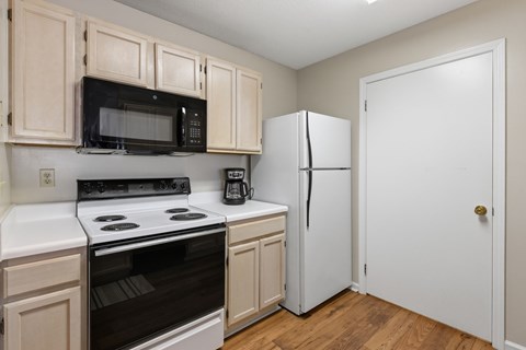 A kitchen with a white oven and black microwave.
