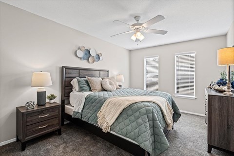 A bedroom with a bed, nightstand, and a ceiling fan.
