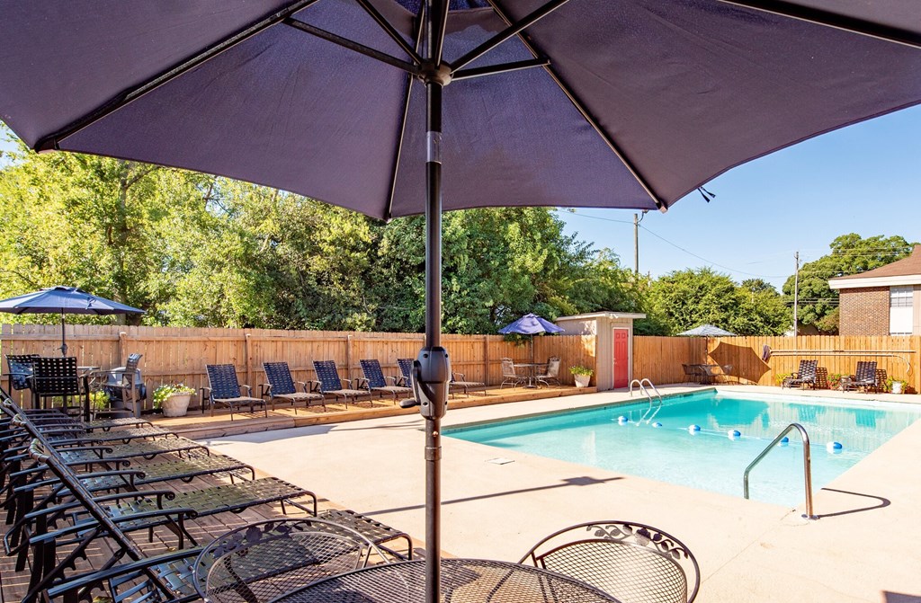 a swimming pool with chairs and an umbrella next to it