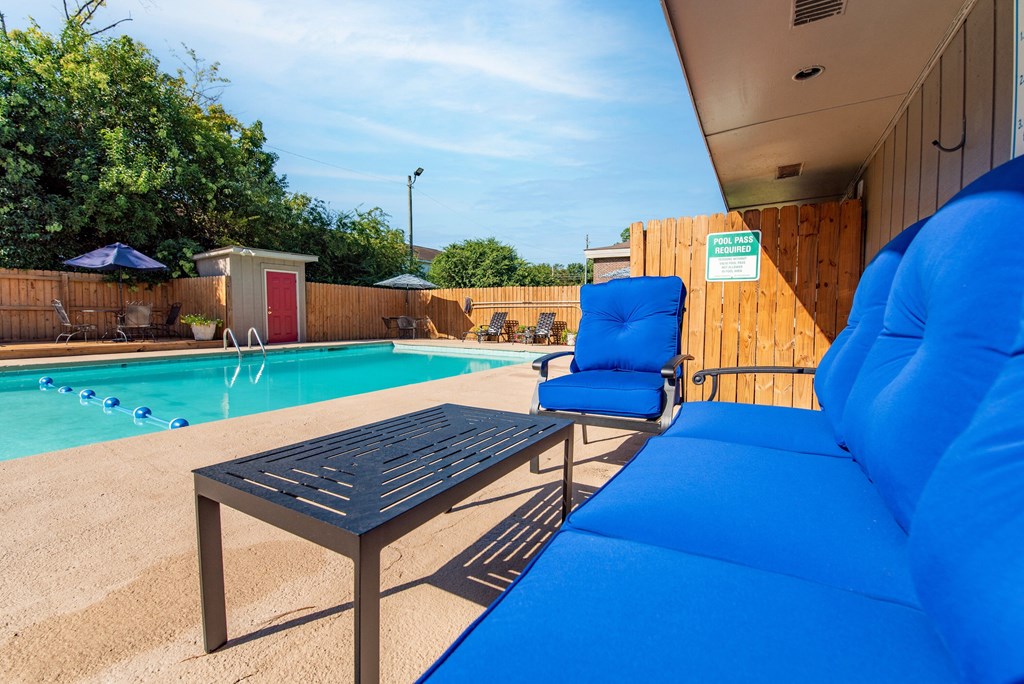 the pool area with a blue couch and chairs next to a pool