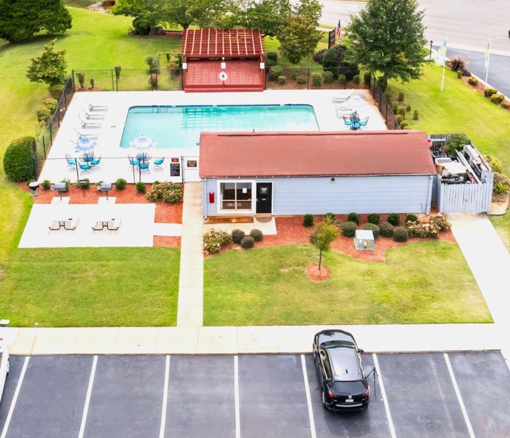 A car is parked in a parking lot in front of a building with a pool.