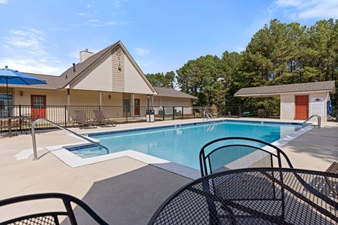 A pool area with a blue pool and a house in the background.