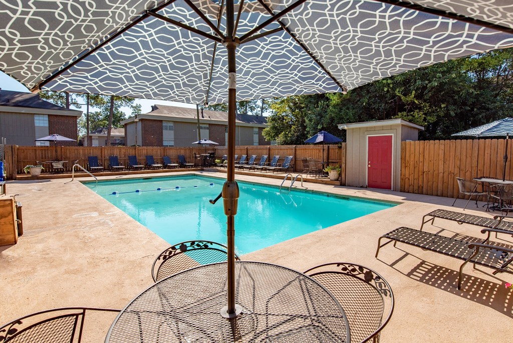 our resort style pool is filled with chairs and an umbrella