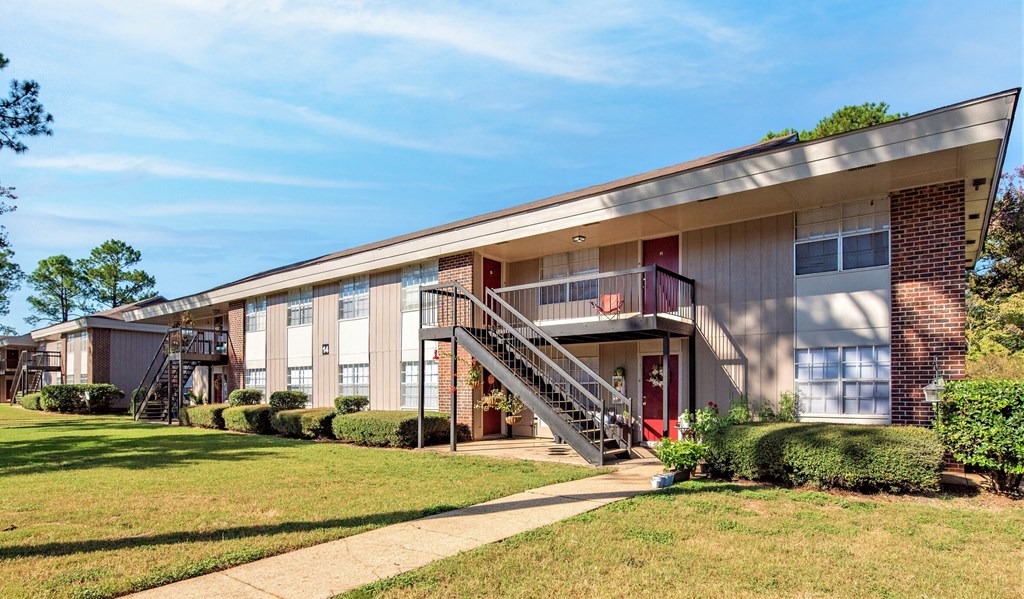an exterior view of a building with stairs and a lawn
