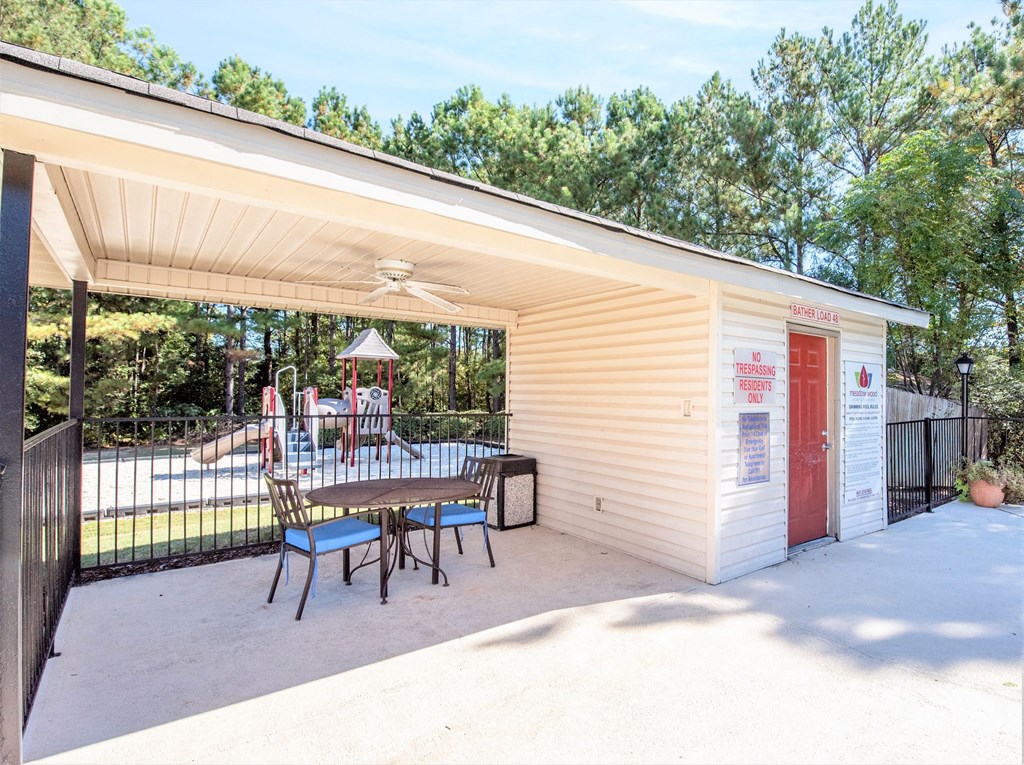 a patio with a table and chairs in front of a pool