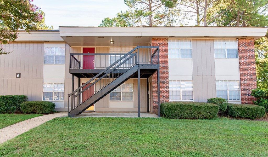 a building with a staircase and a lawn in front of it