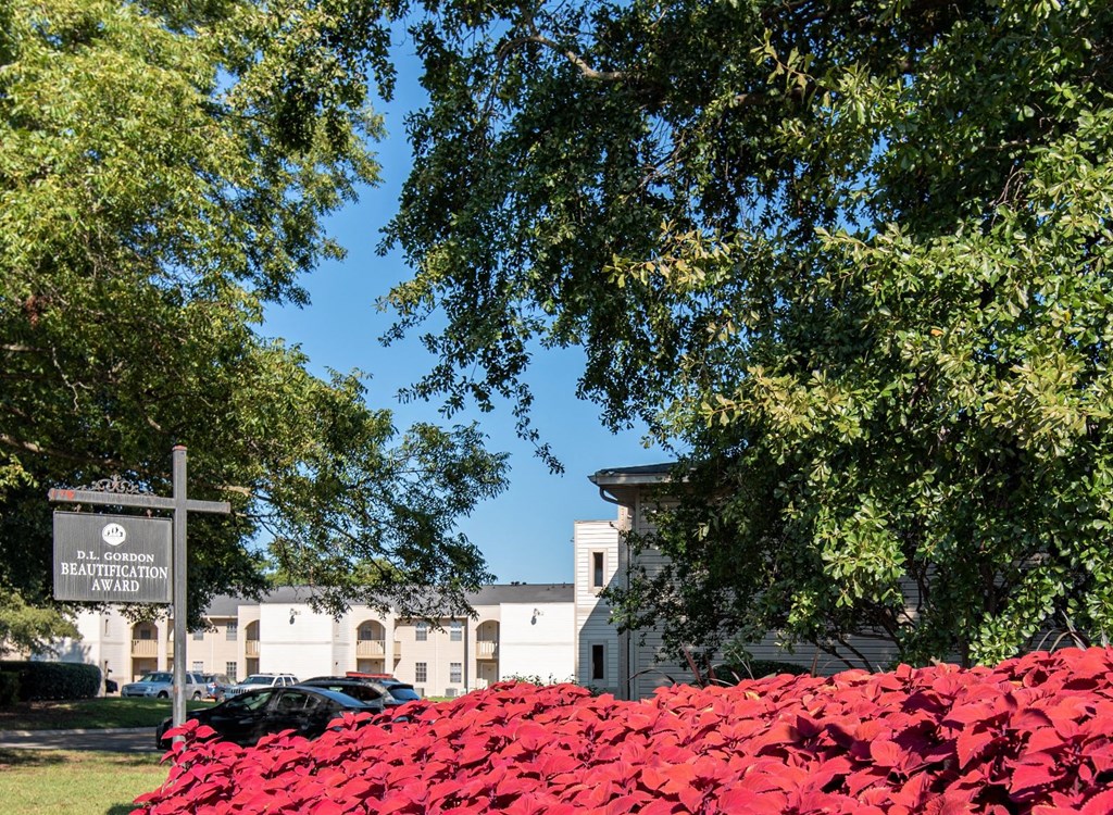 a cross in front of a building with red ivy on the ground