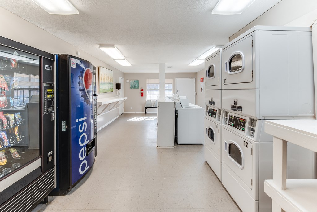 a laundromat with a row of washers and dryers and refrigerators