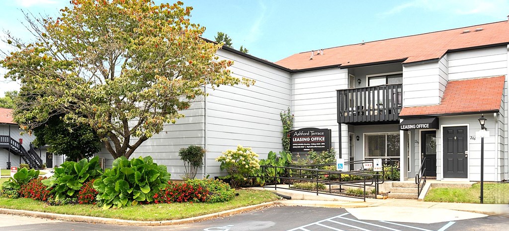 A building with a sign that says "Laurel Cottage" is in front of a tree.