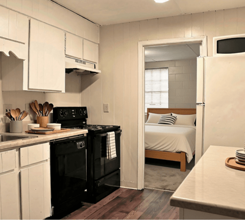 A small kitchen with a black stove and white cabinets.