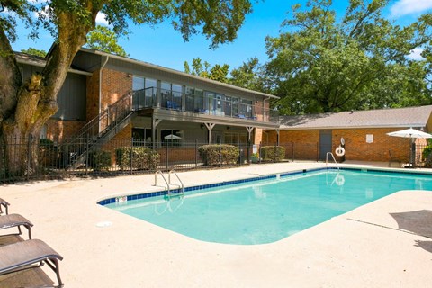 A swimming pool in a backyard with a deck and a tree.
