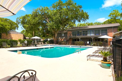 A large outdoor swimming pool surrounded by trees and a building.