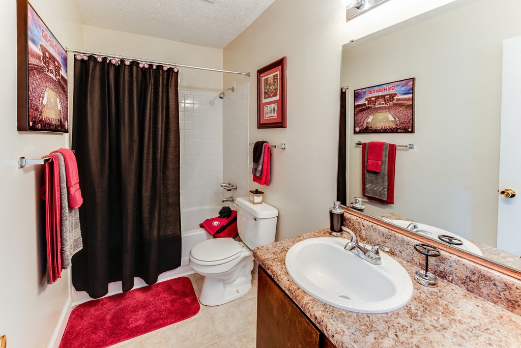 a bathroom with a sink toilet and shower with a black curtain