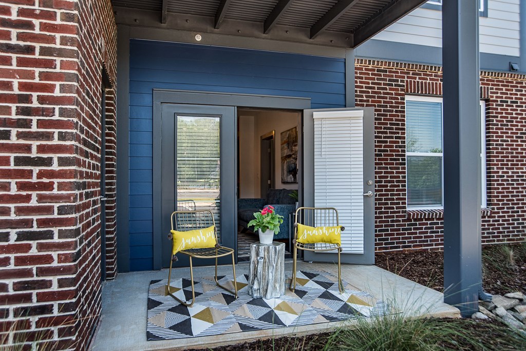 a patio with chairs and a table with flowers on it