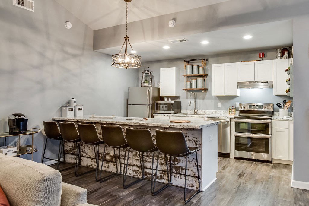 a kitchen with a long bar and a counter top with chairs