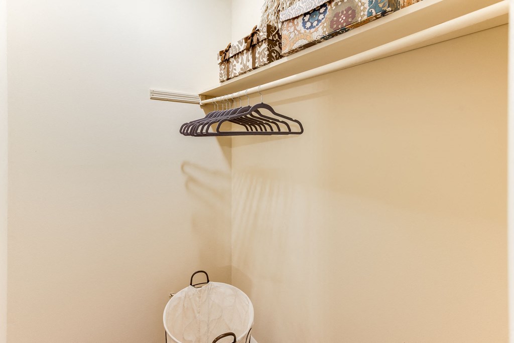 a small laundry room with a white basket and a shelf with a pair of shoes on it