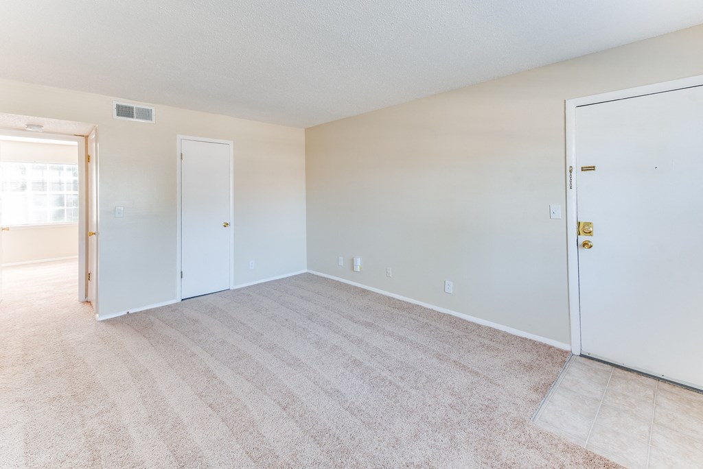an empty living room with a door to a bedroom